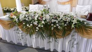 Красивые пастельные и белые цветы с ветвями папоротника украшают стол для жениха и невесты