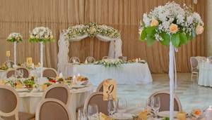 Украшение столов для молодоженов и гостей белыми цветами и зелеными листьями